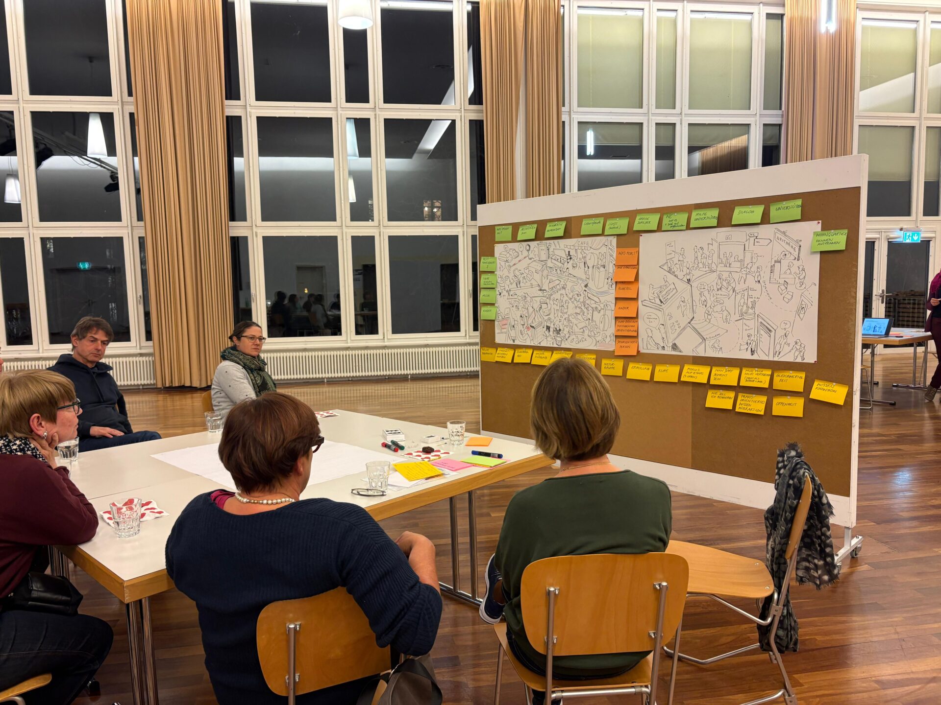 Mehrere Personen sitzen vor einer Pinwand