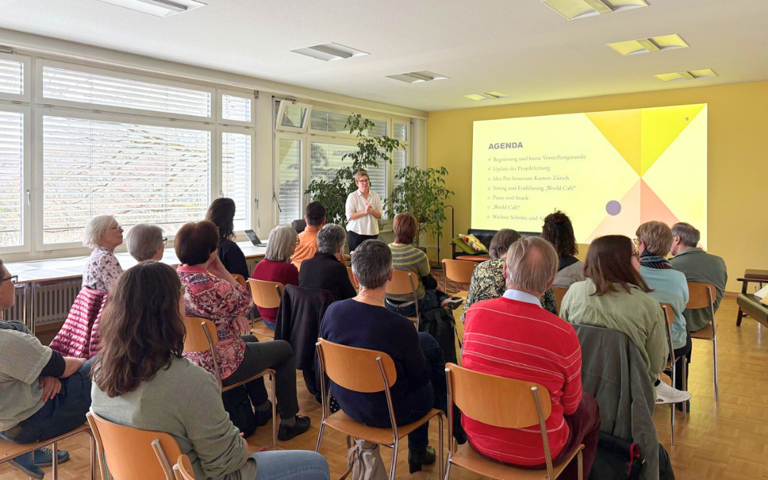 Menschen sitzen auf Stühlen und sprechen miteinander